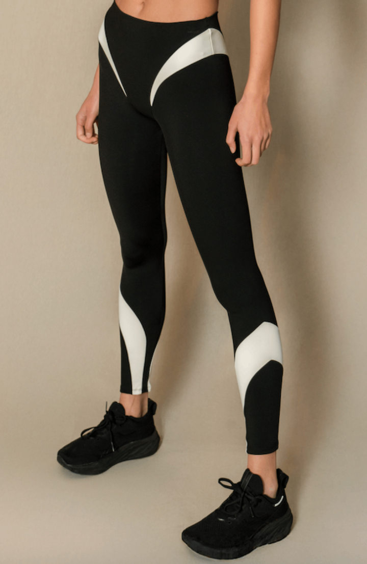 A pair of black leggings with white accents and geometric patterns on the side, worn with black sneakers.