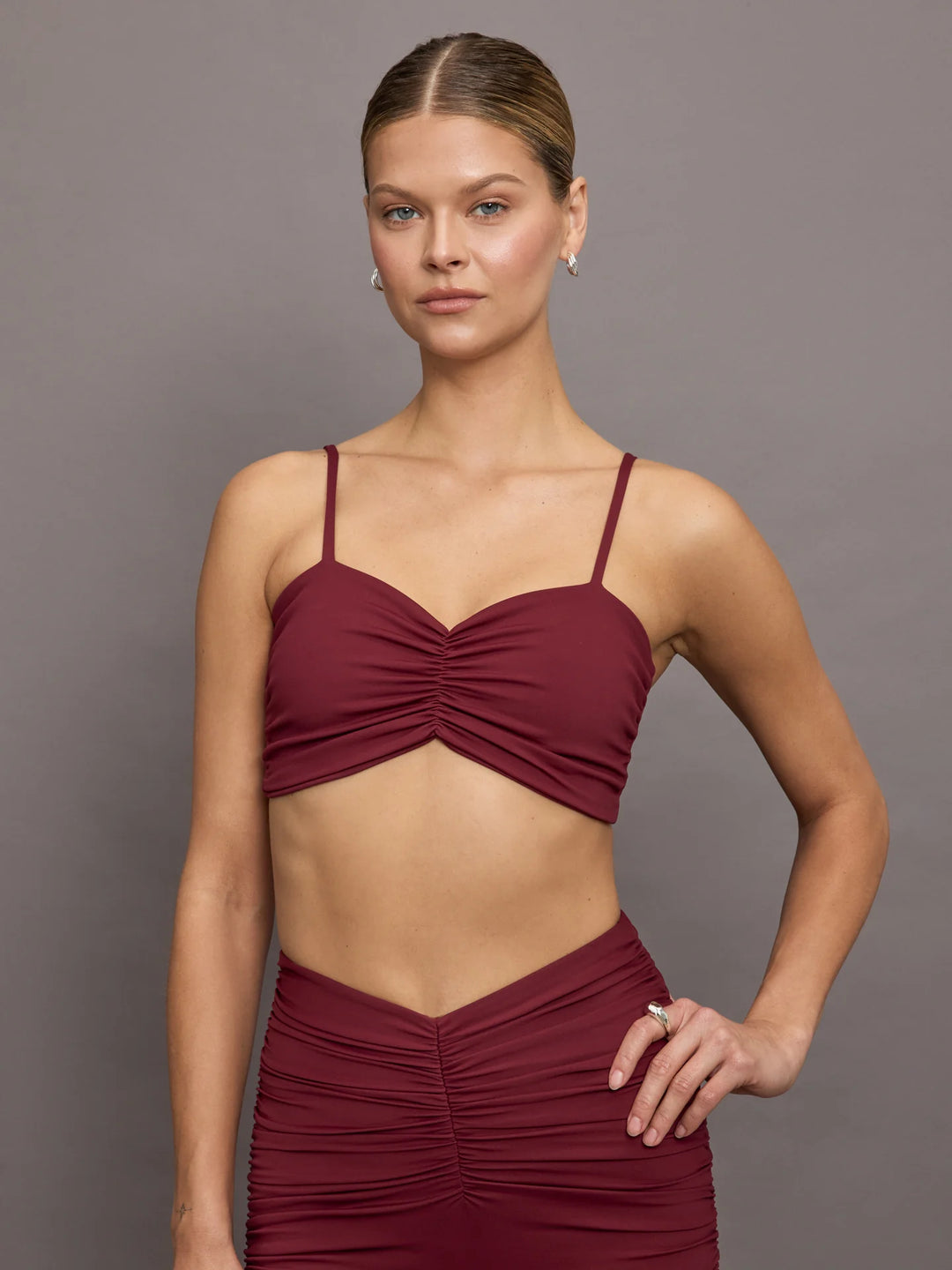 A model wearing a burgundy ruched crop top.
