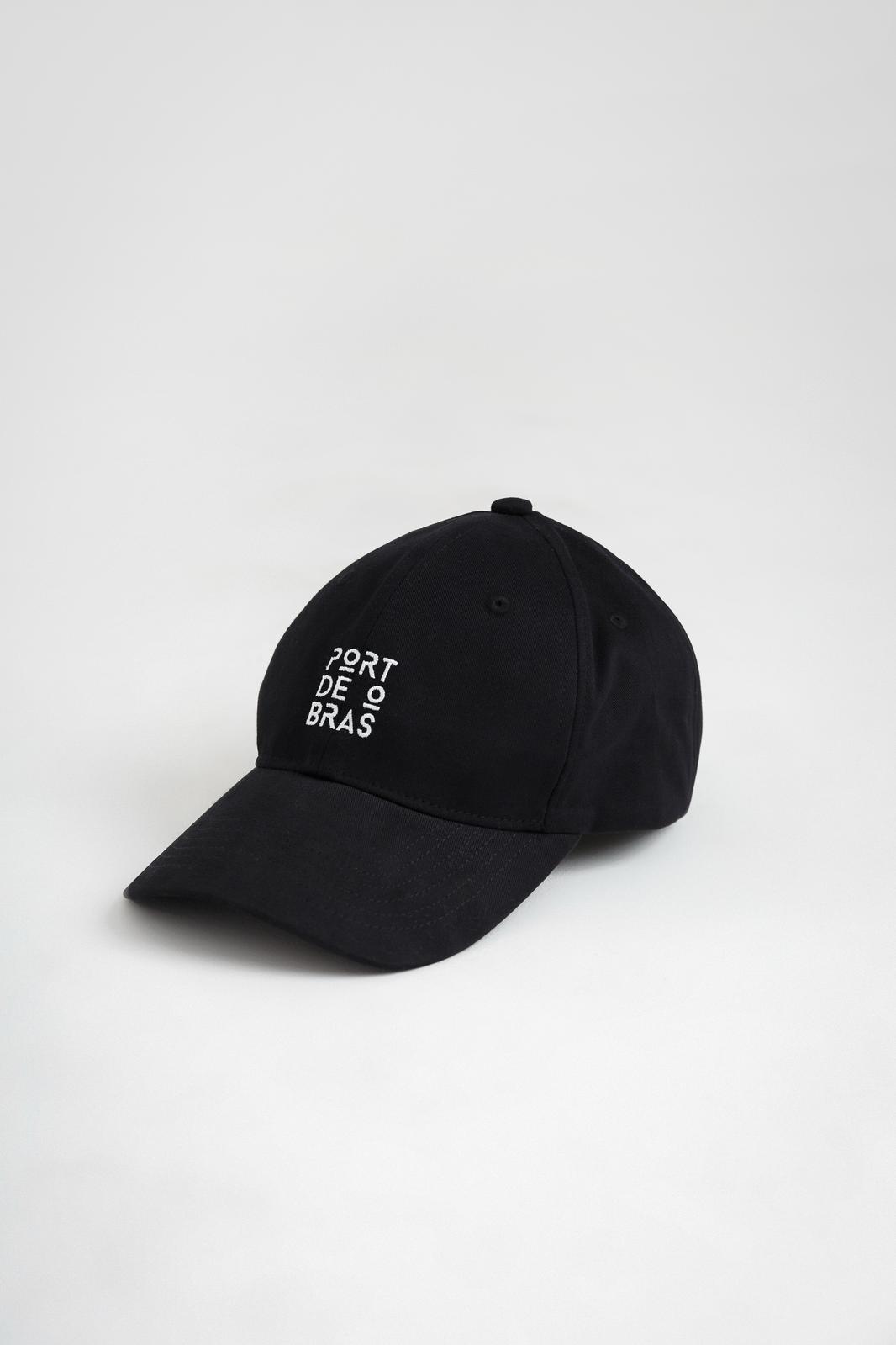 A black baseball cap with the Port de Bras text logo on the front.
