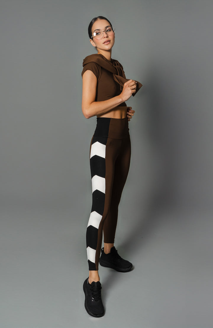 A model wearing high-waisted leggings with a geometric pattern consisting of white arrows on a dark background.