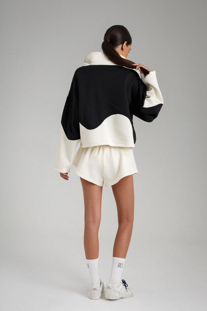 Person wearing a black and white outfit with a plain background