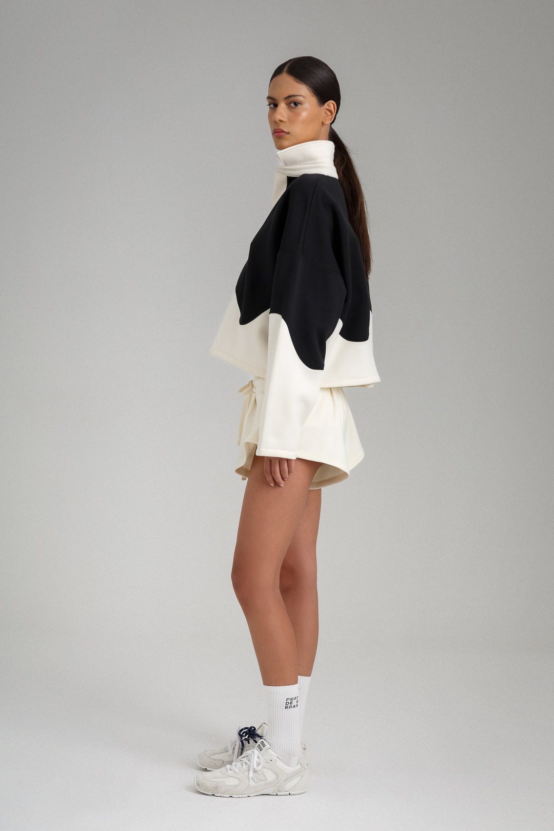 Woman wearing a black and white layered outfit on a gray background
