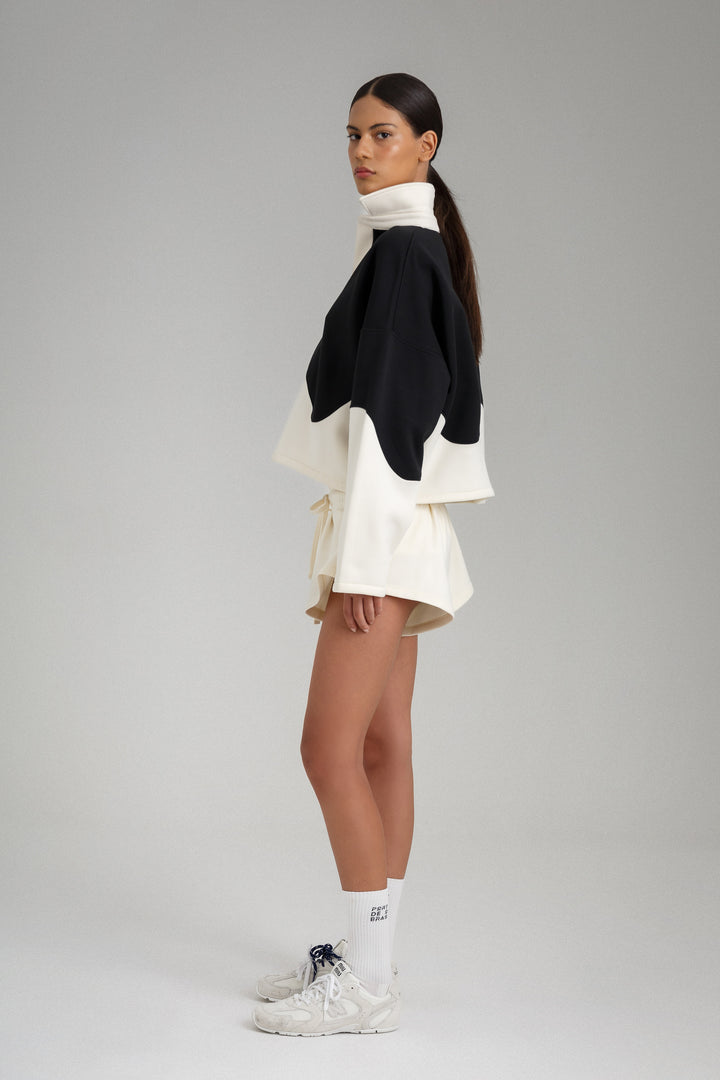 Woman wearing a black and white layered outfit on a gray background