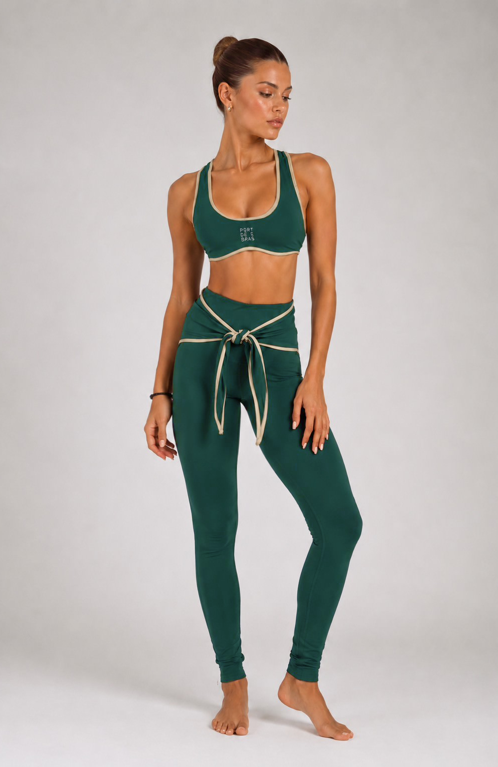 Woman wearing a green sports bra and leggings set on a white background