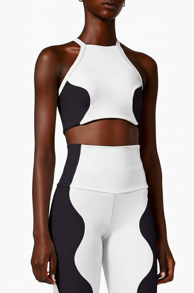 A model wearing a white and black sports crop top with a racerback design.