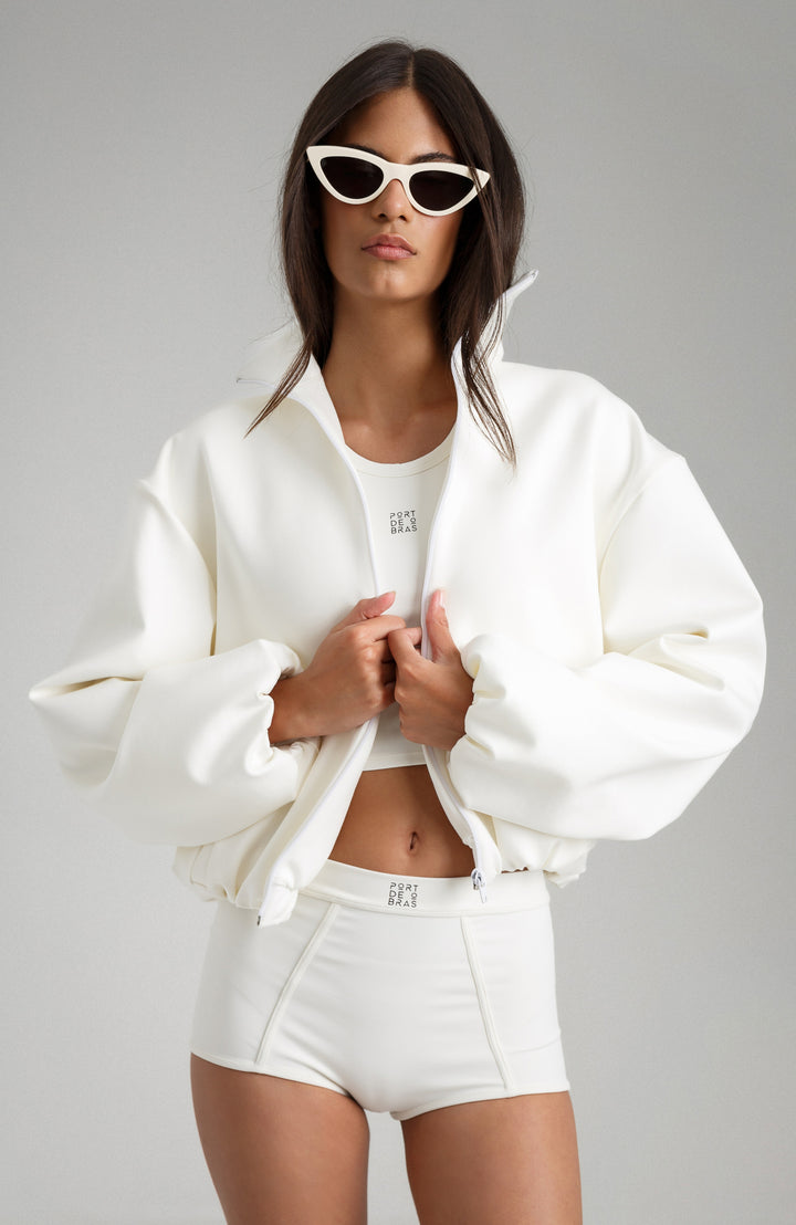 Woman wearing a white outfit with sunglasses on a gray background