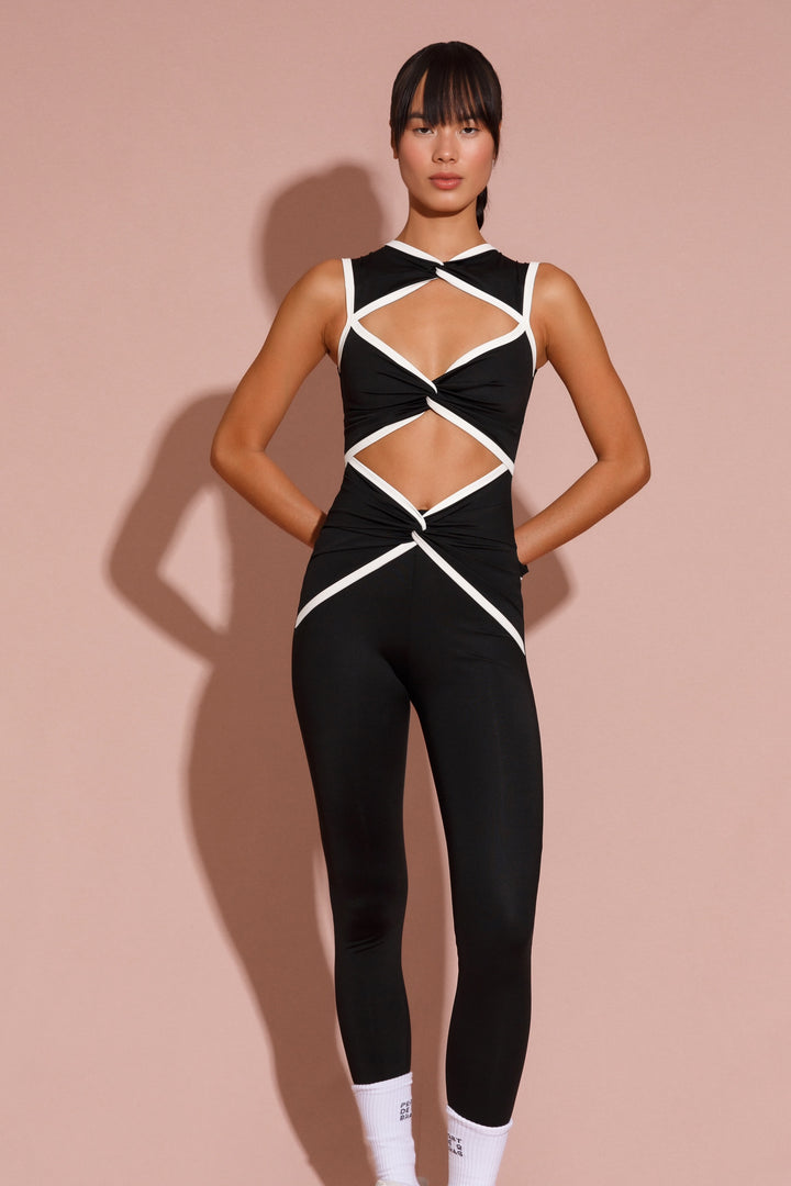 A model wearing a black bodysuit with geometric cutouts and contrasting white rib detailing.