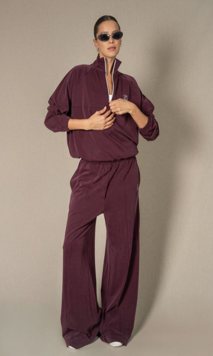 Woman wearing a burgundy tracksuit against a beige background