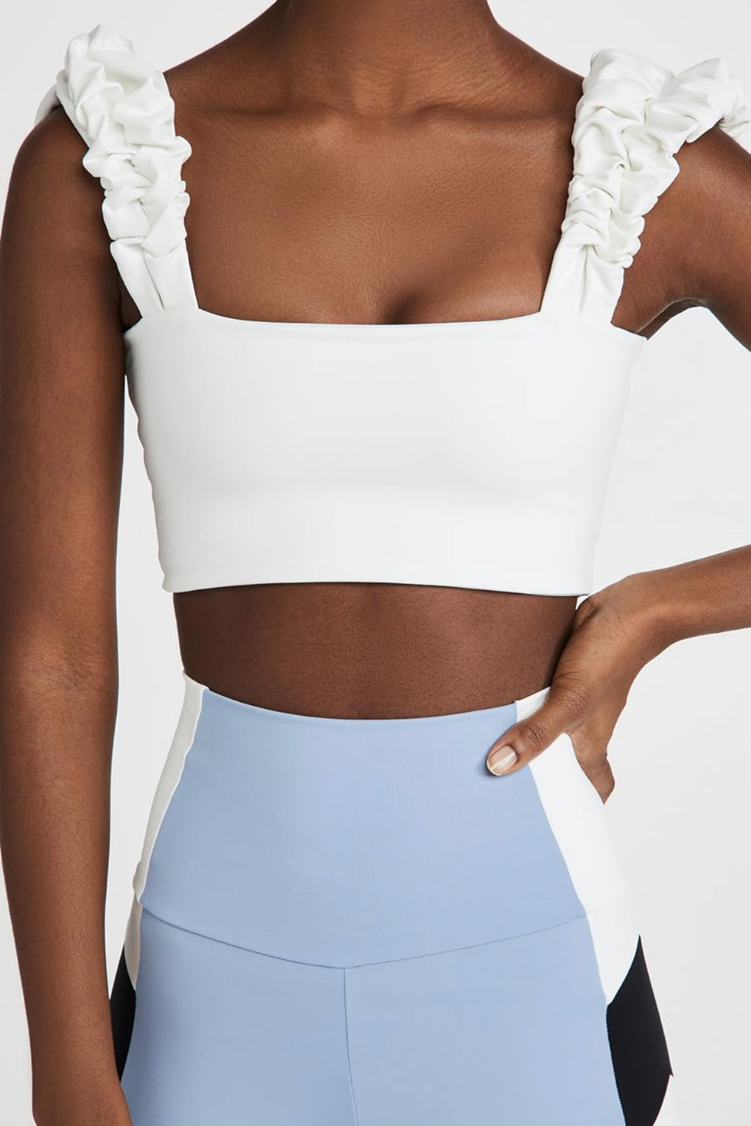 A close-up of a woman wearing a white square-neck scrunchie top with ruffled details on the shoulders.