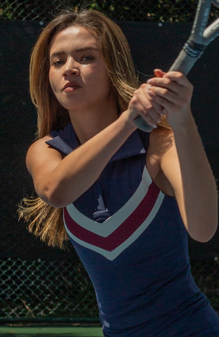 Woman in a blue tennis top holding a tennis racket on a tennis court
