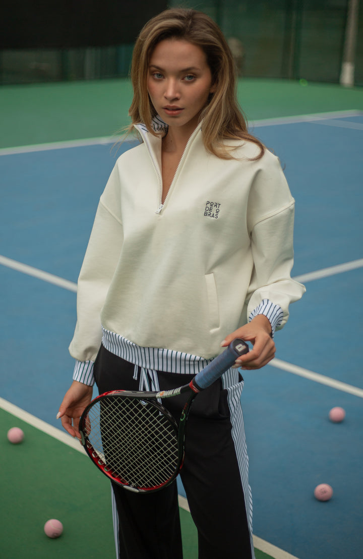 Woman holding a tennis racket on a tennis court with sports balls around