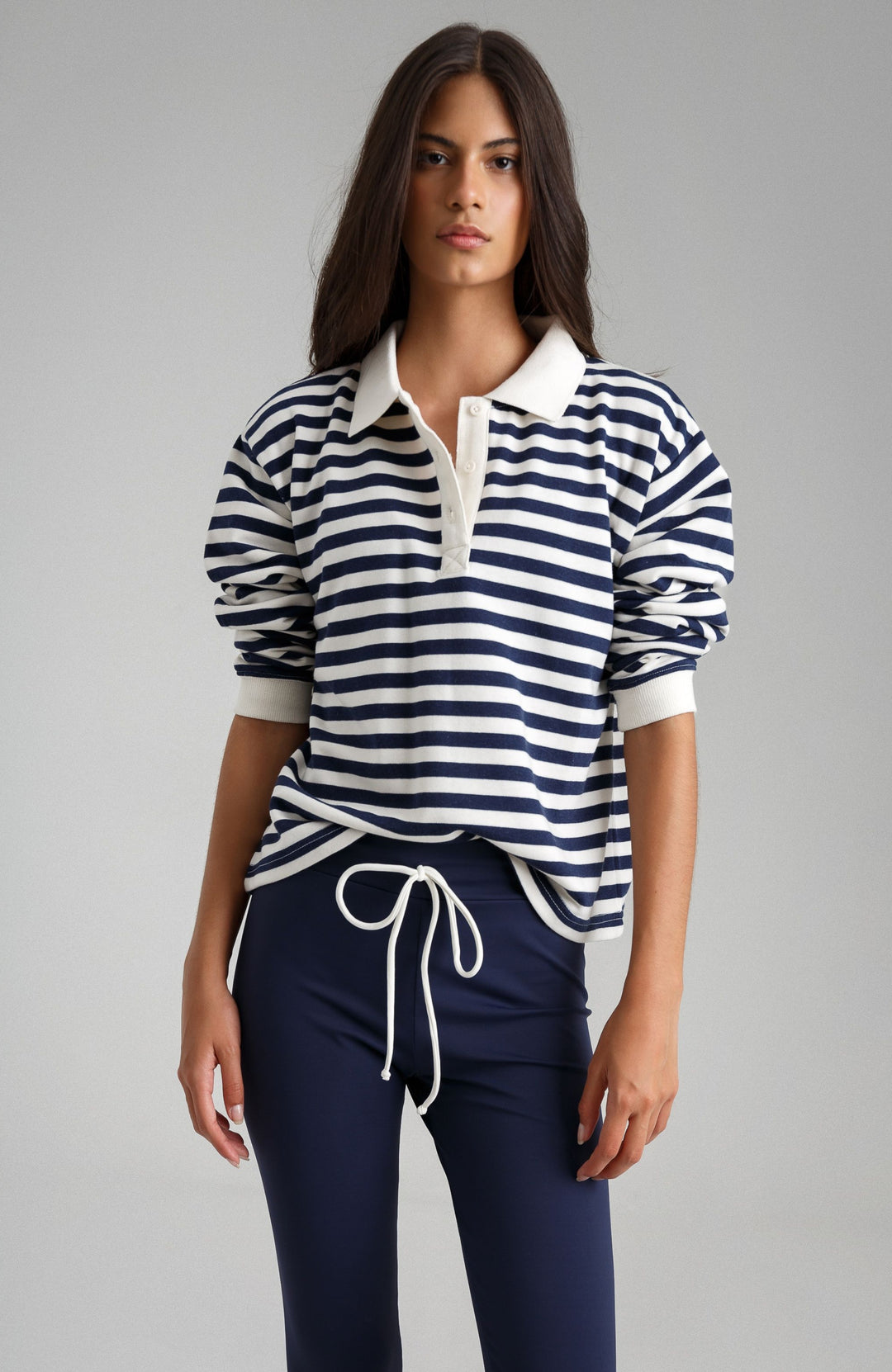 Woman wearing a navy and white striped shirt with a white collar against a gray background