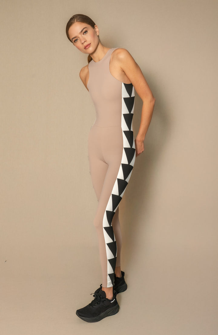 Woman wearing a beige sleeveless unitard with black and white patterns against a beige background