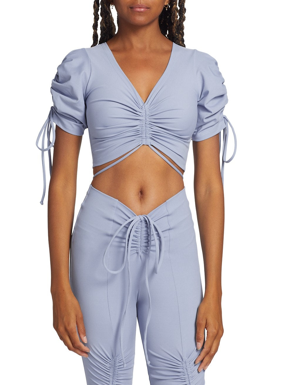 A woman wearing a blue Vero Top with ruched details at the front and down the sleeves, featuring drawstrings.