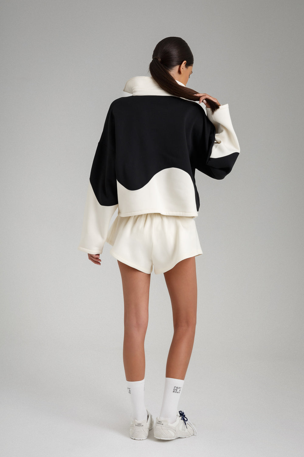 Person wearing a black and white outfit with a plain background