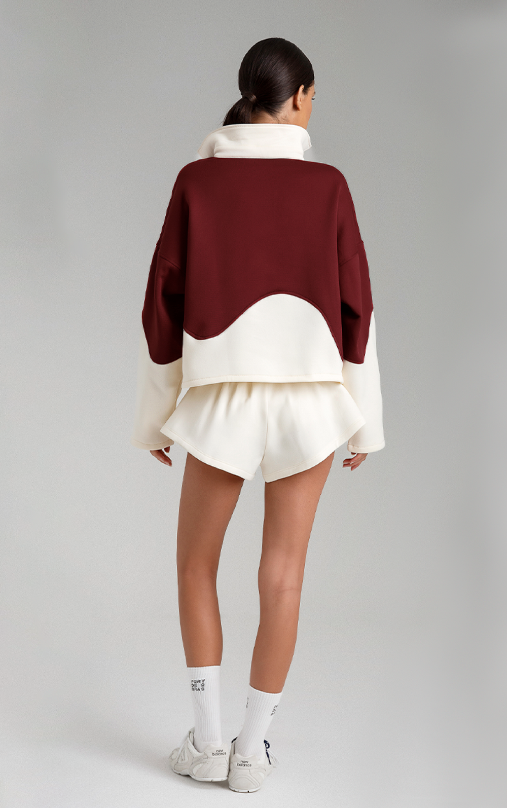 Person wearing a burgundy and white outfit on a gray background